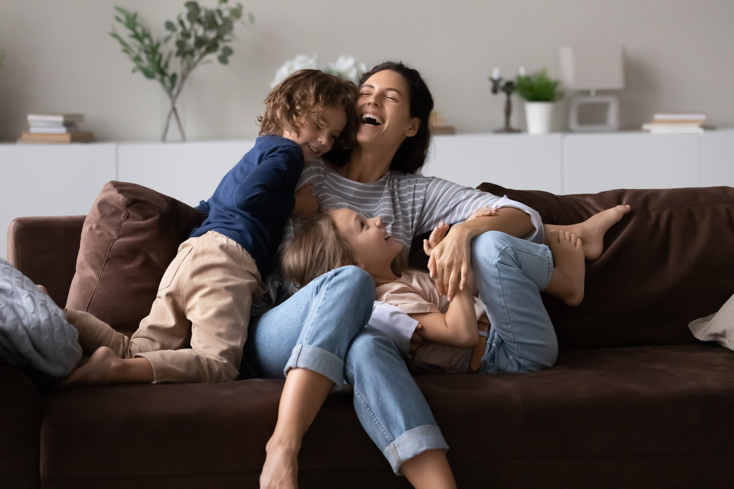 overjoyed mother with two kids having fun on comfortable couch